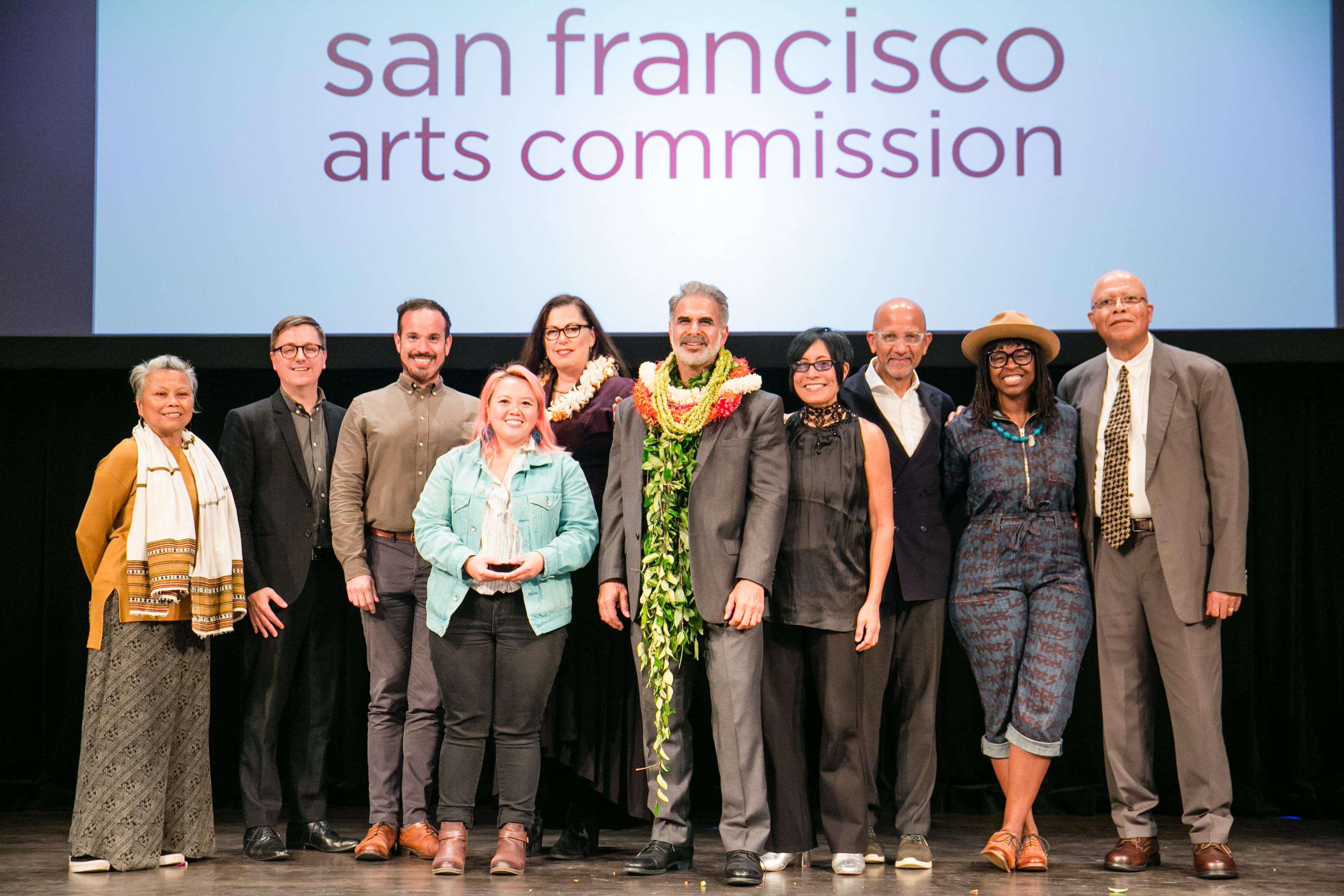 Commissioners, awardees, staff and special guests posing on stage in a group photo at the 4th Annual Grants Convening. Photo: Andria Lo