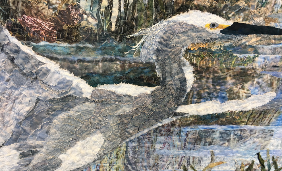 Detail of fabric collage featuring an egret taking flight in a marshland by Merle Axelrod. 