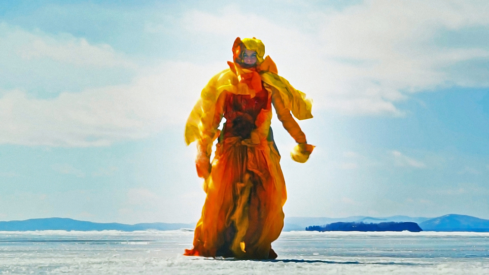 Woman dressed in an orange yellow outfit in an icey landscape