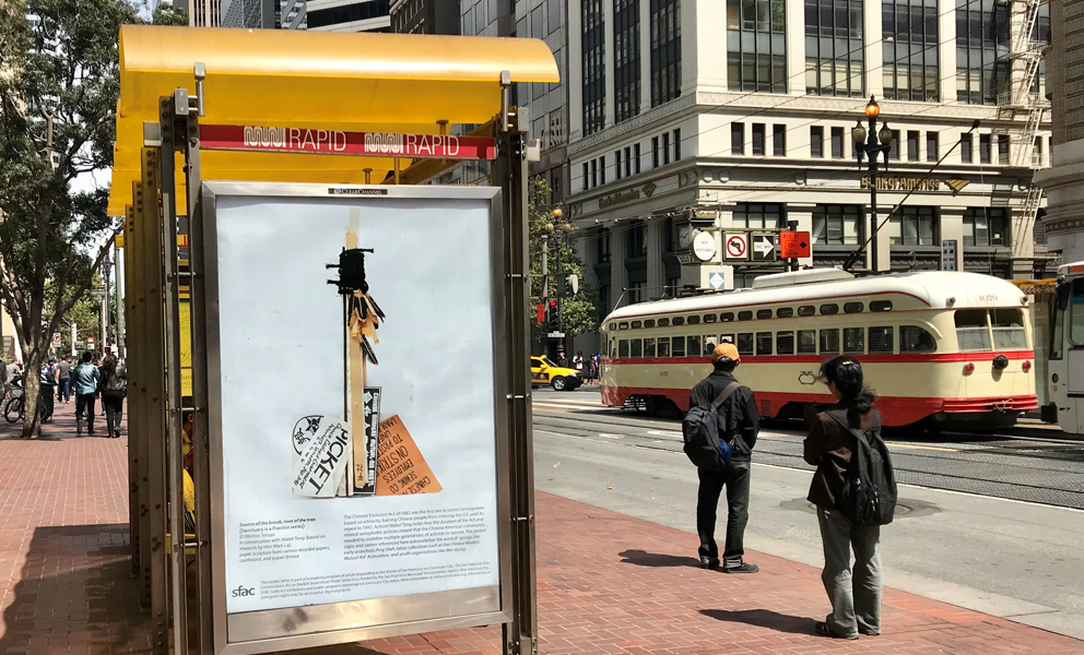 Image of a bus kiosk on Market Street with an image of an amulet by Weston Teruya