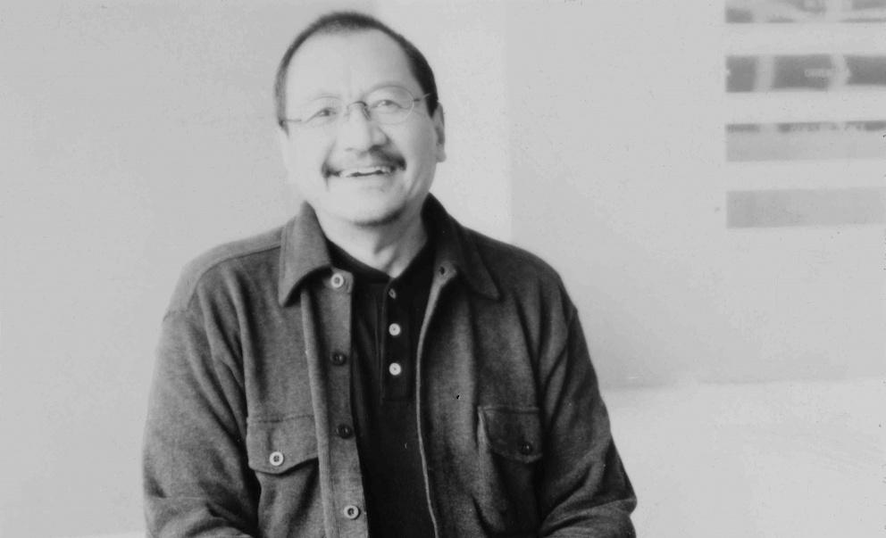 black and white image of the artist with short hair and glasses, smiling